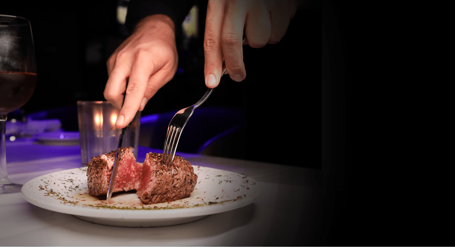 Person cutting steak on white plate