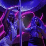 Two women by a pole, neon background