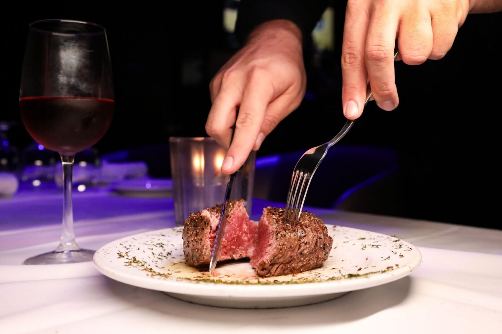 Person slicing steak with a fork and knife
